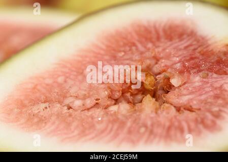 Fresh fig sliced in half with whole figs in the background, on a wooden surface. Fig fruits on a wooden platter. Stock Photo