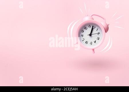 modern pink alarm clock falling on the floor with pink color background Stock Photo