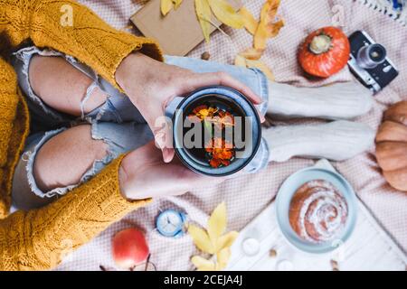 atmospheric autumn background. girl holds cup of coffee. bun, pumpkin, apples, book, headphones, retro camera in frame Stock Photo