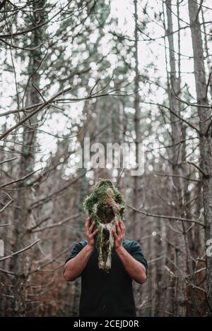 unrecognizable tourist man standing and holding skull with moss in the forest. Stock Photo