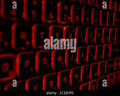 Black computer keyboard with red backlight in the dark. Stock Photo