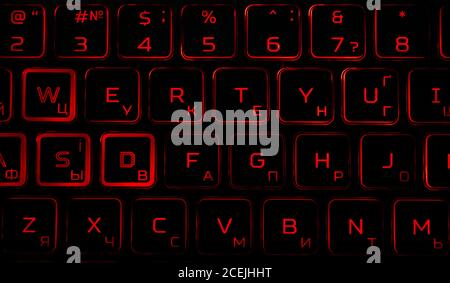Black computer keyboard with red backlight in the dark. Stock Photo