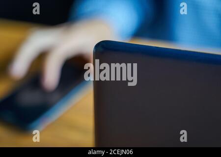 Person working with telephone and laptop. Freelancer sitting at a table with a notebook in the background uses a smartphone. Stock Photo