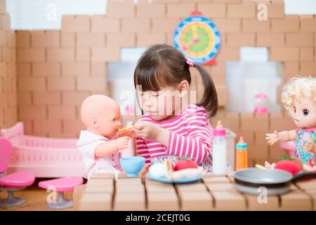 young  girl pretend play babysitting with baby doll at home Stock Photo