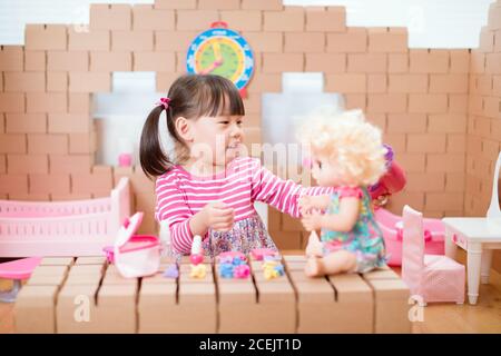 young  girl pretend play babysitting with baby doll at home Stock Photo