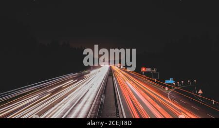 Long exposure shot of bright traces of car lights on busy road at night Stock Photo