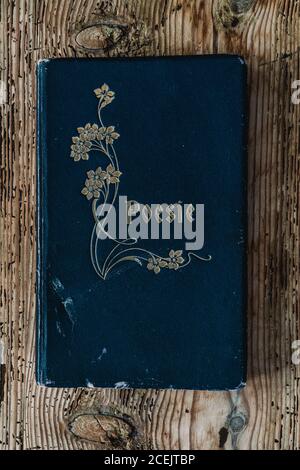 From above view of ancient used blue poem volume placed on wood background Stock Photo