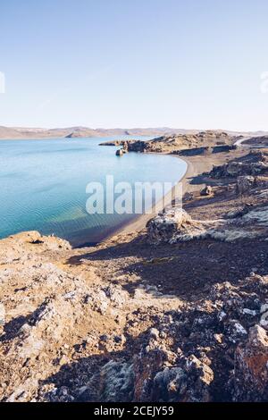 Stone shore of wide river with blue water between hills in Iceland Stock Photo