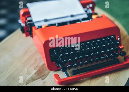 Close-up bright red typewriter on small table with paper sheet inserted Stock Photo