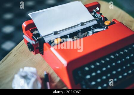Pen and crumpled paper near close-up bright red typewriter with blank paper sheet inserted Stock Photo