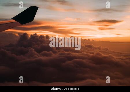 Clouds and plane wing in sunset Stock Photo