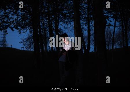 man using smartphone in dark forest Stock Photo