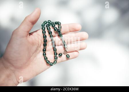 Closeup shot of crop hand holding green beads on blurred background Stock Photo