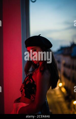 Side view passionate attractive brunette Woman looking at camera on balcony in evening Stock Photo
