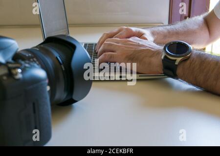 man processes photos on laptop after downloading them from camera Stock Photo