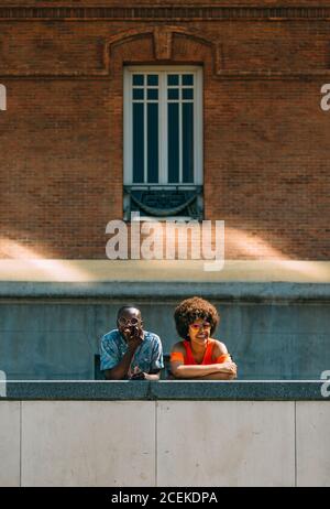 smiling black couple leaning on border in city Stock Photo