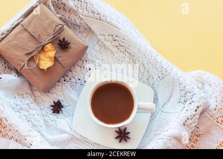 Cup of coffee or cocoa on a tray, gift in a box, white knitted napkin, star anise. Autumn concept Stock Photo