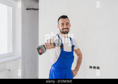 A young foreman holds a drill in his hand. He smiles and looks at the camera Stock Photo