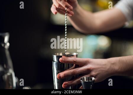 The hands of a professional bartender pour red syrup into a measuring glass  of jigger, next to a metal tool for preparing and stirring alcoholic cockt  Stock Photo - Alamy