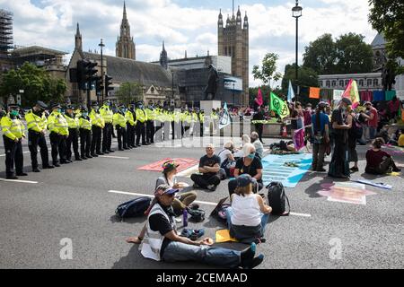 London, UK. 1st September, 2020. Metropolitan Police officers monitor climate activists from Extinction Rebellion occupying roads around Parliament Square during a Back The Bill rally. Extinction Rebellion activists are attending a series of September Rebellion protests around the UK to call on politicians to back the Climate and Ecological Emergency Bill (CEE Bill) which requires, among other measures, a serious plan to deal with the UK’s share of emissions and to halt critical rises in global temperatures and for ordinary people to be involved in future environmental planning by means of a C Stock Photo