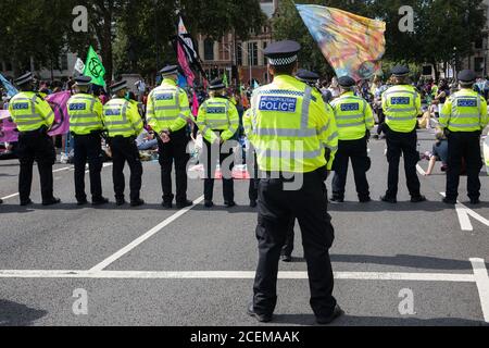 London, UK. 1st September, 2020. Metropolitan Police officers monitor climate activists from Extinction Rebellion occupying roads around Parliament Square during a Back The Bill rally. Extinction Rebellion activists are attending a series of September Rebellion protests around the UK to call on politicians to back the Climate and Ecological Emergency Bill (CEE Bill) which requires, among other measures, a serious plan to deal with the UK’s share of emissions and to halt critical rises in global temperatures and for ordinary people to be involved in future environmental planning by means of a C Stock Photo