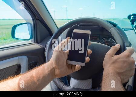 Man using cellphone while driving. Using the navigator on smartphone while traveling. Stock Photo