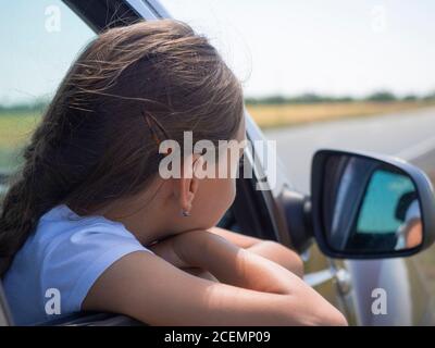 Little girl looking at the view outside the car. Close-up photo. Stock Photo