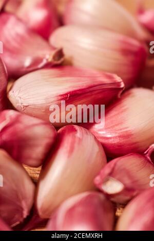 closeup of a set of loose purple garlic cloves on a wooden background. Stock Photo