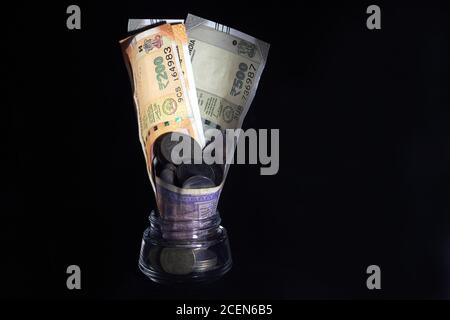 New and old Indian currencies. 50, 100, 200, 500 rupee notes and coins. Indian currency isolated on black background. Stock Photo