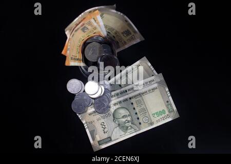 New and old Indian currencies. 50, 100, 200, 500 rupee notes and coins. Indian currency isolated on black background. Stock Photo