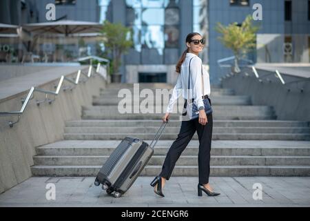 Dark-haired stylish woman walking down the street Stock Photo