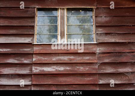 Louvered windows in an old cobweb covered timber wall of an ancient and abandoned country community hall Stock Photo