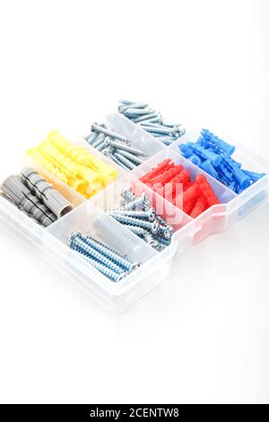Box with screws and dowels of different sizes, shapes and colors on a white background. Stock Photo