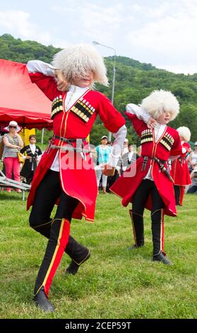 Adygea, RUSSIA - JULY 25 2015: Children in the Circassian national costumes dancing on green grass folk dances of Adygeai. Ethnic festival in the foot Stock Photo