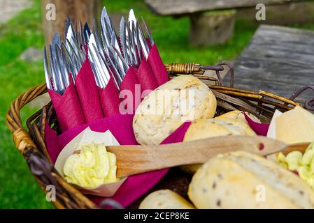 Soft bun bread, forks and knifes is served with the butter in the wicker basket in the restaurant . Stock Photo