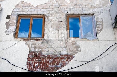 derelict building with two windows and broken plaster Stock Photo