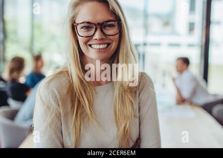 Portrait of happy businesswoman with colleagues in boardroom. Smiling woman with coworkers in conference room having meeting. Stock Photo