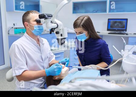 Male doctor dentist treating teeth using dental microscope instruments Stock Photo