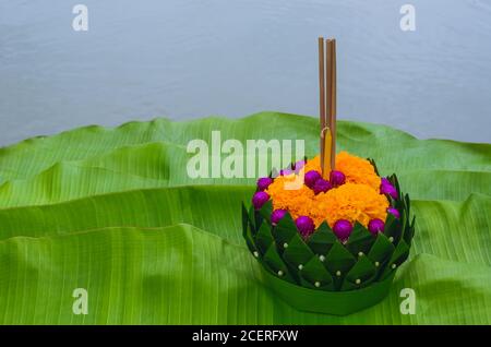 Banana leaf Krathong that have 3 incense sticks and candle decorates with flowers for Thailand full moon or Loy Krathong festival puts on green banana Stock Photo