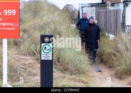 A couple walk along an england coast path dog walking route, camber, east sussex, uk Stock Photo