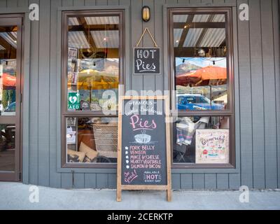 A sign advertising Fairlie bakery pies and the shop window at a cafe in Glenorchy New Zealand Stock Photo