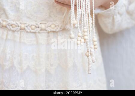 Handmade macrame dress belt. Natural cotton threads and wooden beads. Stylish decoration for women 's dress.  Macrame braiding and cotton threads. Fem Stock Photo