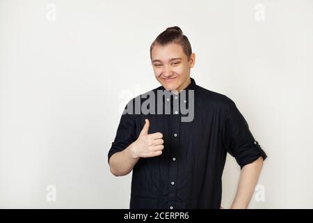 Young man, guy student in black shirt showing thumb up with a happy smile. All is well, it shows success. OK Stock Photo