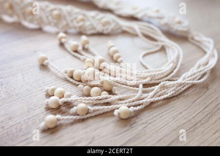 Handmade macrame dress belt. Natural cotton threads and wooden beads. Stylish decoration for women 's dress.  Macrame braiding and cotton threads. Stock Photo