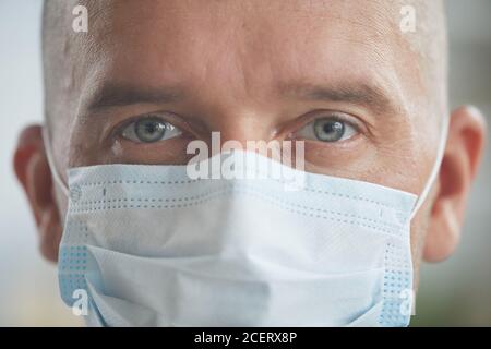 Horizontal close-up portriat shot of unrecognizable Caucasian man wearing protective mask on his face looking at camera Stock Photo