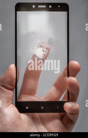 crack on the glass from over-tapping the screen by the user. the human face is pressed against the glass of the phone.screen is broken. Stock Photo