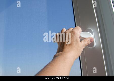 woman opens a window with a mosquito net Stock Photo