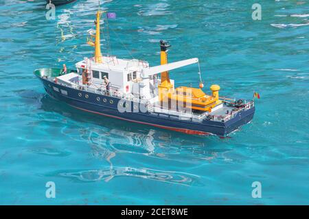 remote control model tugboat sails on clear blue water Stock Photo