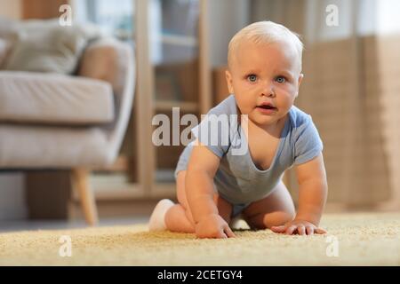 Portrait of cute little child wearing blue clothes crawling on fours looking at camera, copy space Stock Photo