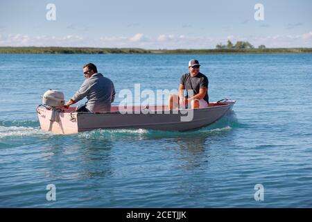 Two men in a small outboard-powered boat on a lake Stock Photo - Alamy